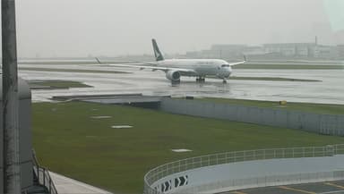Wet tarmac and Cathay Pacific plane at rainy Hong Kong airport