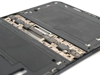 Close-up, at an angle, of an opened iPhone Duo with its inner screen removed, showing interlocking metal hinge links and plates running across the middle of the dark frame.