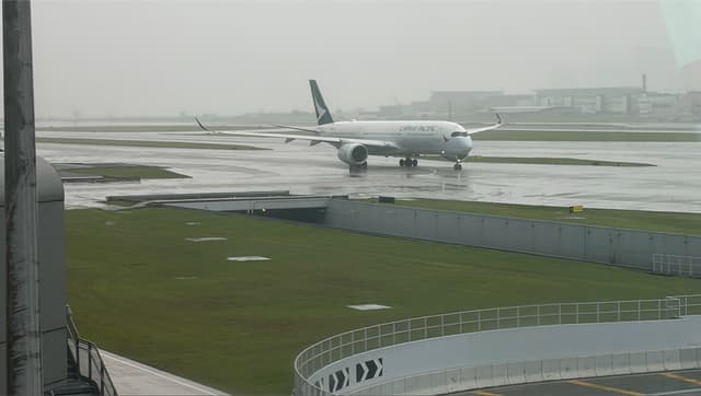 Wet tarmac and Cathay Pacific plane at rainy Hong Kong airport