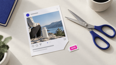 A printed social media post mockup beside blue-handled scissors and a pink #PR sticker on a white desk with a notebook and