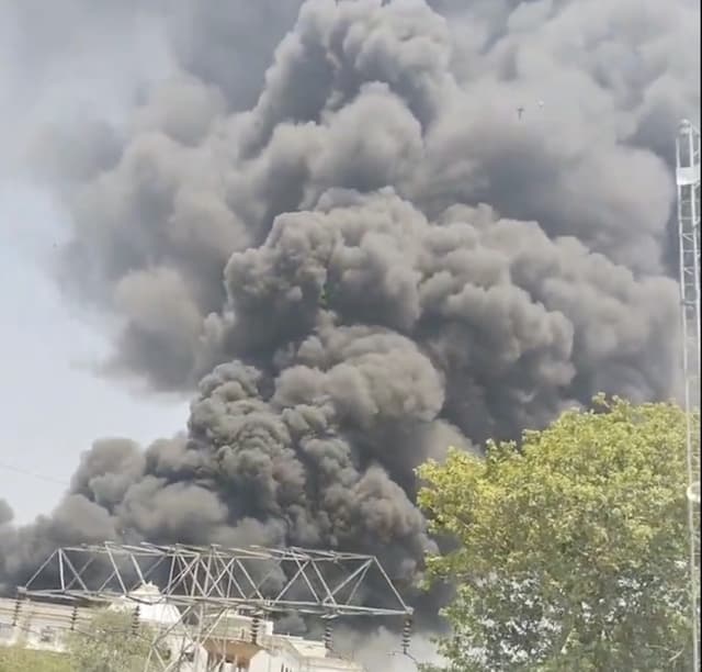 A large plume of thick black smoke rising into the sky